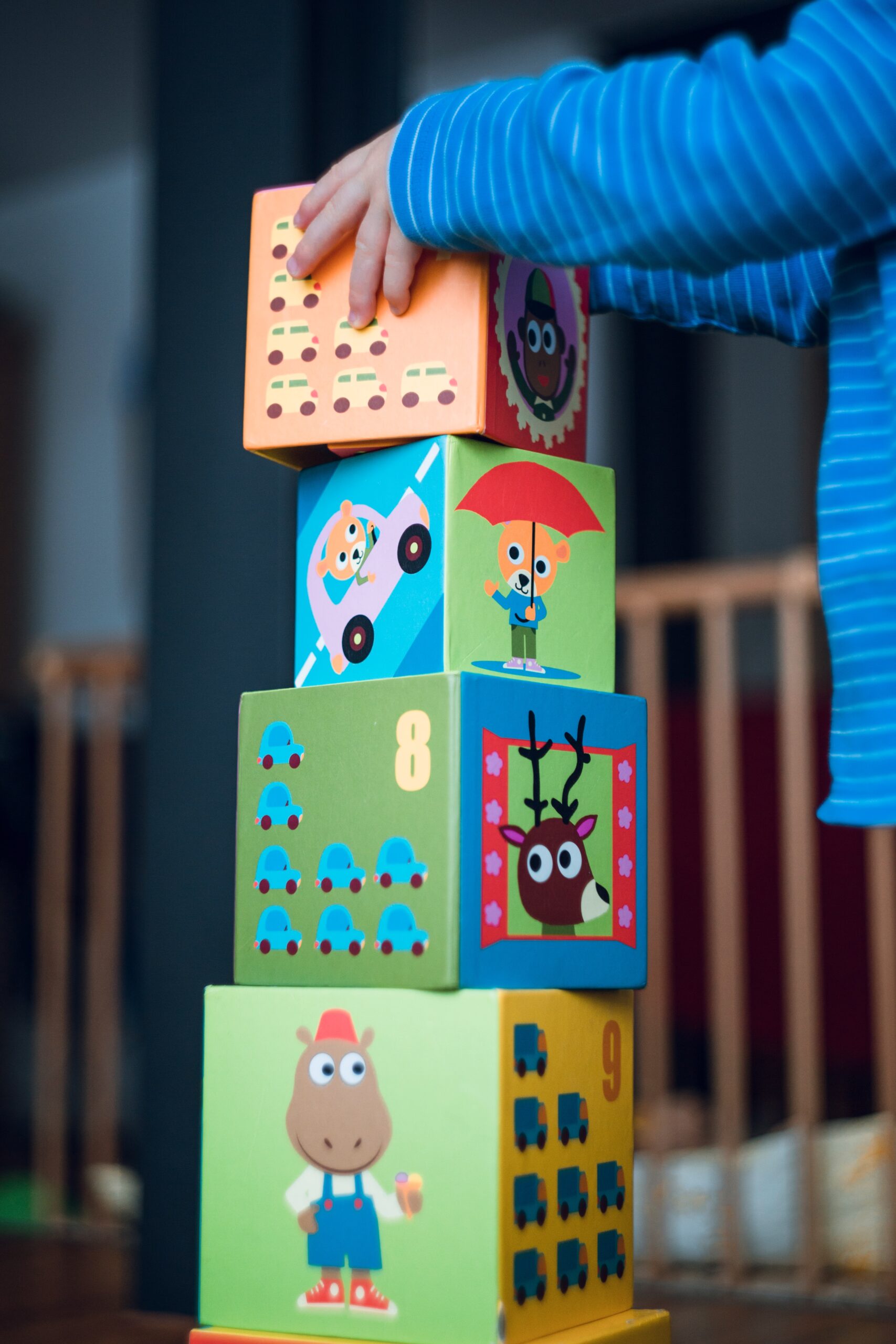 An image showcasing a child's hands grasping Montessori wooden blocks of various shapes and sizes, forming a tower, while the child's face radiates joy and concentration